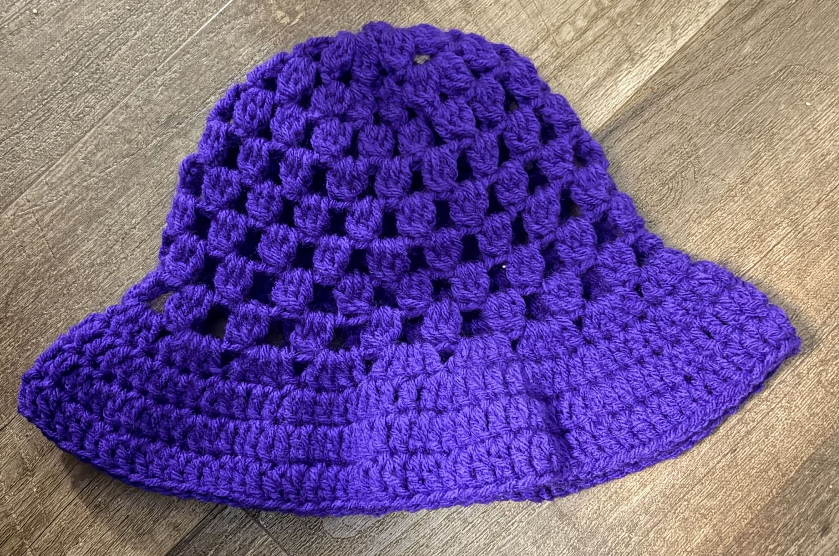 Purple crocheted hat on a wooden surface